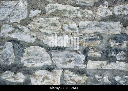Ancient grey round stone wall flat background closeup Stock Photo