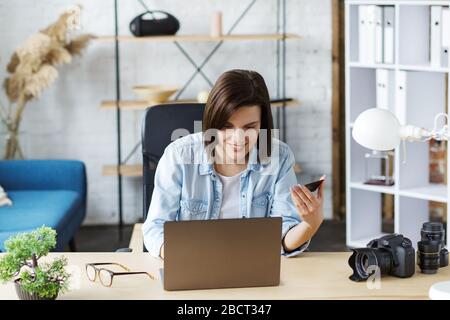 Young freelancer in home office holding credit card and using laptop. Online shopping, online payments. Booking tickets online. Modern technologies Stock Photo