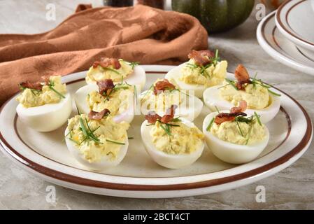 A plate of deviled eggs with chives and bacon bits Stock Photo