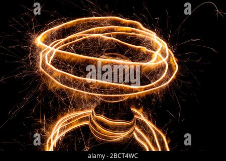 Light painting with a sparkler circling around a glass ball on a black background. Stock Photo