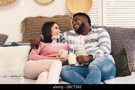 Man and woman sit on sofa and laugh Stock Photo