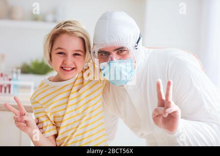 father in protective medical suit having fun, hugging with infected, contagious boy, visiting hospitalized son Stock Photo