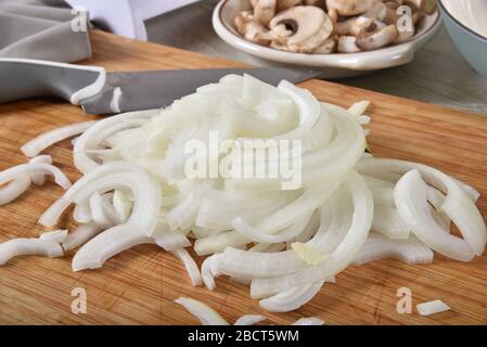 Thin sliced onions on a cutting board with sliced mushrooms Stock Photo