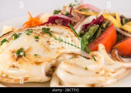 Plate of grilled cuttlefish with mixed salad with tomato, lettuce, carrot and heart of palm. Stock Photo