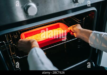 A woman puts a cake in the oven Stock Photo