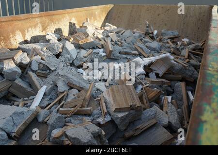 Building waste and debris from a demolished building, pieces of mortar, wood, polystyrene and concrete mostly in grey color in a bit waste container Stock Photo