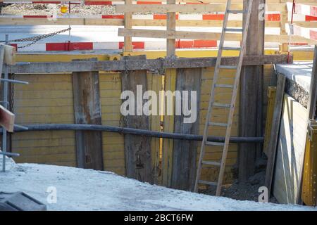 supporting of civil engineering building site or construction site with wooden boards, the whole site iss secured by barrier planks in red and white a Stock Photo