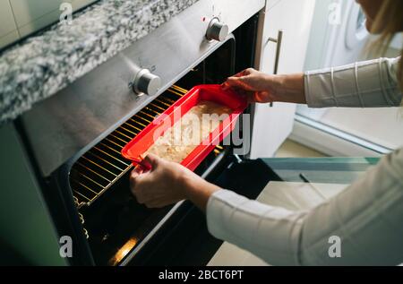 A woman puts a cake in the oven Stock Photo