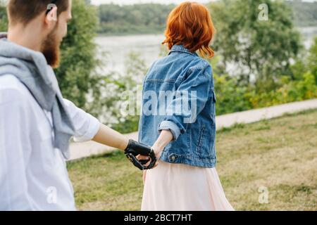 Couple strolling in a park, woman pulling a man by the hand Stock Photo