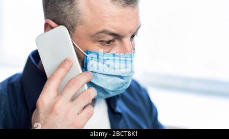 Man Talking On Phone Wearing Protective Medical Mask At Home Stock Photo