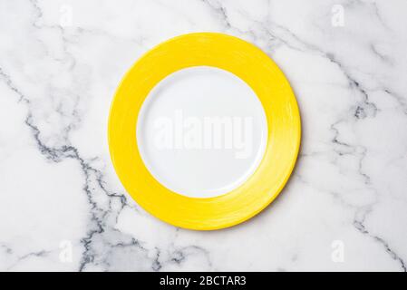 Empty Yellow Plate On Marble Background. Top View Copy Space For Text or Design. Table Setting Stock Photo