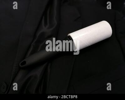 Dust remover tool with reusable sticker cleaning black fabric suit Stock Photo
