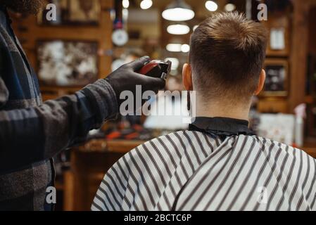 Barber in hat cuts the client 's hair 