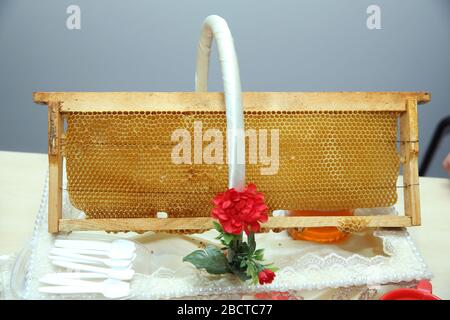 wooden honey dipper and honeycombs in wooden frame with full cells of honey sealed with wax, tools for beekeeping on wooden table. Beekeeping concept Stock Photo