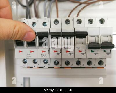 Male finger switching circuit breakers inside electrical panel cabinet Stock Photo