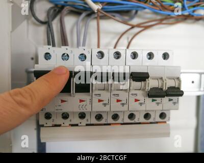 Male finger switching circuit breakers inside electrical panel cabinet Stock Photo