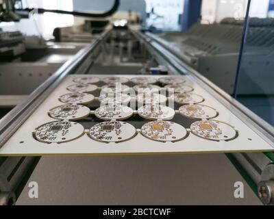 PCB assembly first stages. PCB on the rails of production line inside pick and place machine Stock Photo