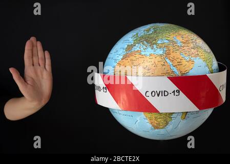 Stop the coronavirus. Hand imposes stop to spread of coronavirus, COVID-19. Planet earth with caution barrier tapes. In the foreground Europe, Africa Stock Photo