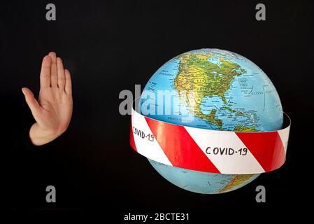 Stop the coronavirus. Hand imposes stop to spread of coronavirus, COVID-19. Planet earth with caution barrier tapes. In the foreground the United Stat Stock Photo