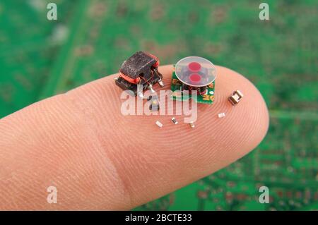 Modern electronics surface mount components in comparison to human finger Stock Photo