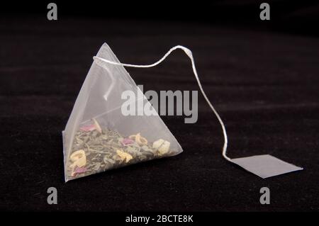 Teabag in the pyramid shape on the dark background Stock Photo