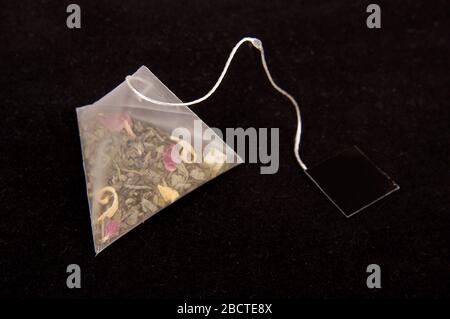 Teabag in the pyramid shape on the dark background Stock Photo