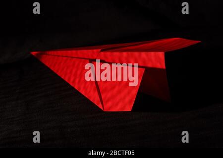 Paper plane folded from red paper on the dark black background Stock Photo