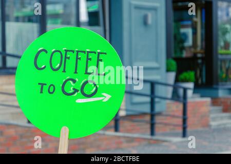 coffee to go sign is located on a green wooden advertising board on the street. coffee concept. coffee to go Stock Photo