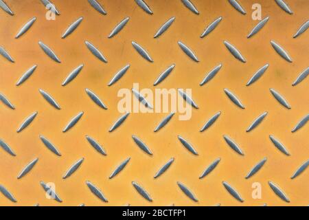 steel sheet metal plate with embossed diamond pattern with orange paint and scratches. polished metal performances Stock Photo