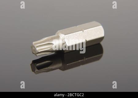 Professional mechanical screwdriver bit close up on the dark reflective background Stock Photo
