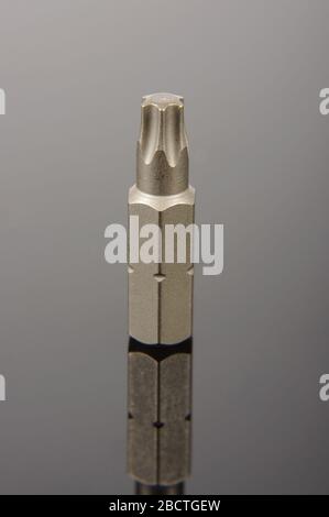 Professional mechanical screwdriver bit close up on the dark reflective background Stock Photo