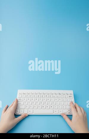 Woman working on a laptop on a blue background., concept of remote maintenance, internet shopping. Stock Photo