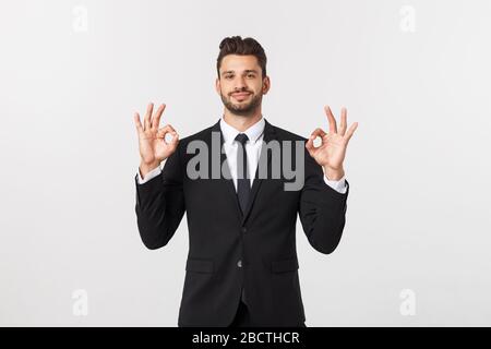 Handsome smiling businessman showing ok sign with fingers over gray background. Stock Photo