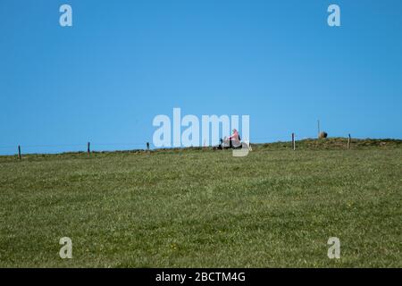 green meadow under the blue sky, motor bike behind  a fence on a country road, no clouds Stock Photo