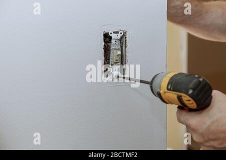 Replacement of the old switch with a new one in closeup of hand of electrician installing wall outlet Stock Photo