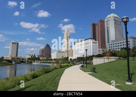 Alexander park Downtown Columbus Ohio green landscape with green trees, concrete walk way , colorful trees city skyline structure ,blue sky Stock Photo