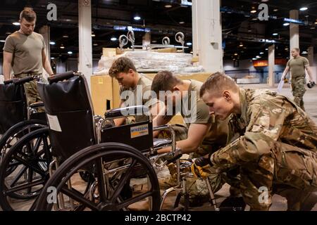 Members of the Illinois Air National Guard assemble medical equipment at the McCormick Place Convention Center in response to the COVID-19 pandemic in Chicago, Ill., March 30, 2020. Approximately 30 members of the Illinois Air National Guard were activated to support the US Army Corps of Engineers and the Federal Emergency Management Agency (FEMA) to temporarily convert part of the McCormick Place Convention Center into an Alternate Care Facility (ACF) for COVID-19 patients with mild symptoms who do not require intensive care in the Chicago area. (U.S. Air Force Photo by Senior Airman Jay Grab Stock Photo