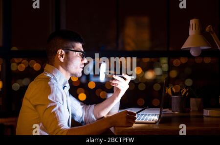 Serious Entrepreneur Using Loudspeaker Talking On Cellphone In Modern Office Stock Photo