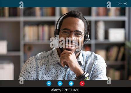 African man wear headset sit at desk looking at camera Stock Photo