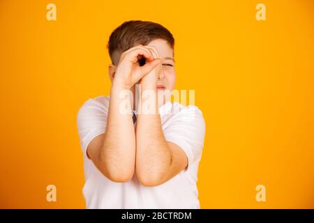 The boy looks like through binoculars. Hands folded into a straw. Boy is watching looking through hands Stock Photo