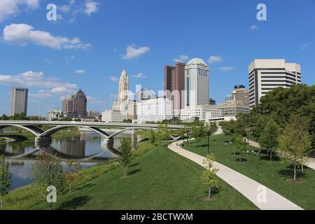 Alexander park Downtown Columbus Ohio green landscape with green trees, concrete walk way , colorful trees city skyline structure ,blue sky Stock Photo