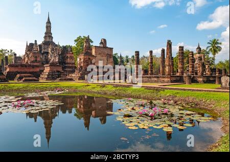 The Wat Mahathat temple reflecting in a pond with lotus flowers, Sukhothai, Thailand. Stock Photo