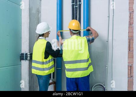 Construction workers measuring pipes on site Stock Photo