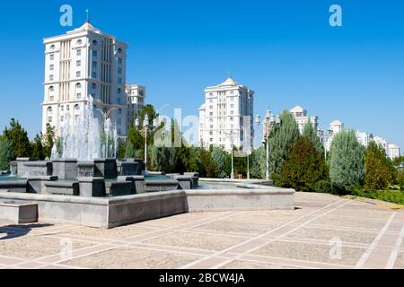 Square in Ashgabat, Turkmenistan showing water fountain and multiple newly-erected white marble residential buildings behind. Stock Photo