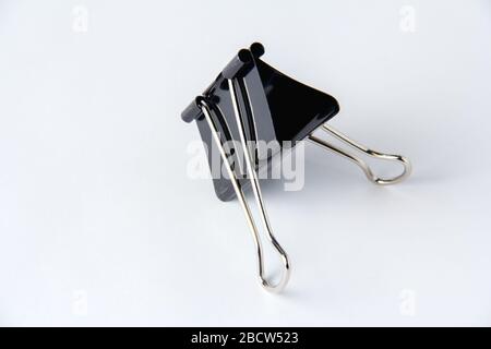Large black paper clip for papers on white background. Stacking papers Stock Photo