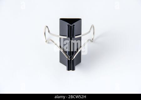 Large black paper clip for papers on white background. Stacking papers Stock Photo