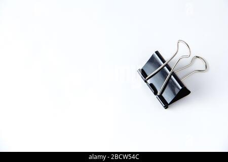 Large black paper clip for papers on white background. Stacking papers Stock Photo