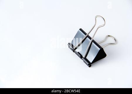 Large black paper clip for papers on white background. Stacking papers Stock Photo