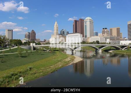 Alexander park Downtown Columbus Ohio green landscape with green trees, concrete walk way , colorful trees city skyline structure ,blue sky Stock Photo