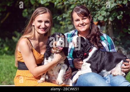 Two girlfriends having fun with dogs in the animal sanctuary Stock Photo